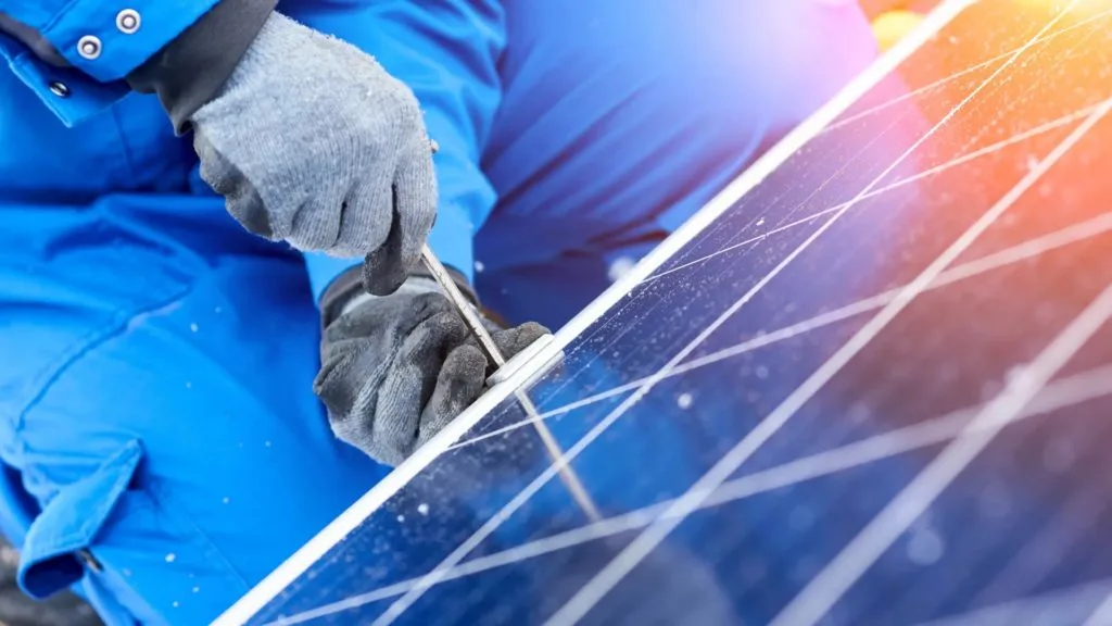 Close-up of gloved hands securing a solar panel connector