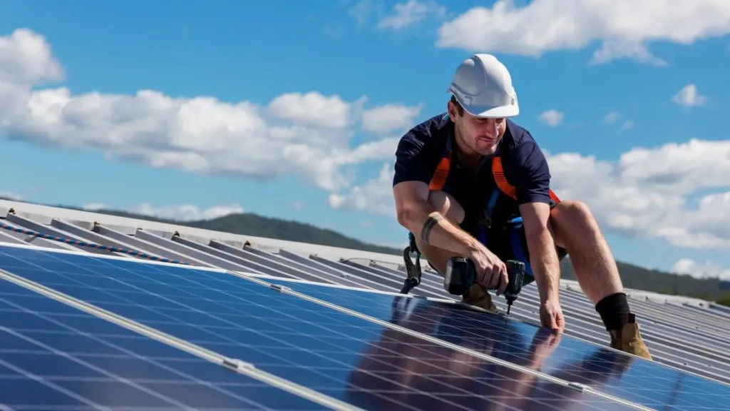 Installer drilling into a rooftop solar panel mounting rail
